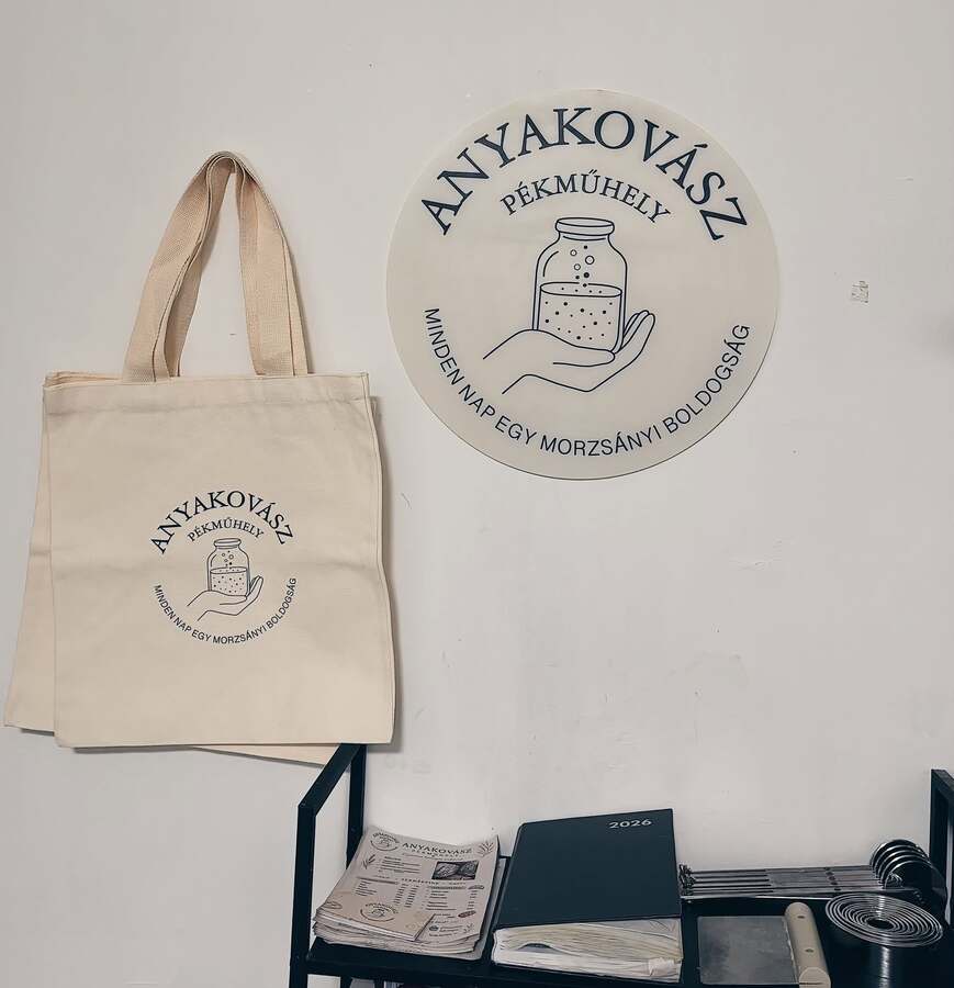 A műhely fala a pékség logós táblájával, alatta vászontáska és árlapok